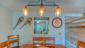 A dining area with a wooden table, chairs, and a ceiling light fixture. - Loon Mountain Condo- Walk to Main Street! (Lincoln)