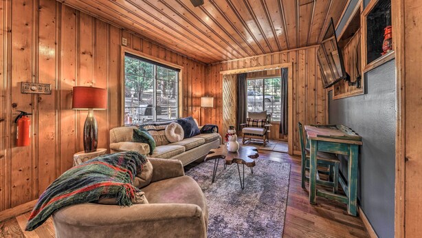 Ein gemütliches Blockhaus-Interieur mit Holzwänden und -decken, einer Couch, einem Couchtisch und einem Essbereich.