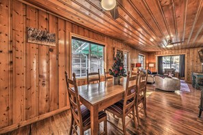 Ein Holzinterieur mit einem Esstisch, Stühlen, einem Weihnachtsbaum und einem Kamin.