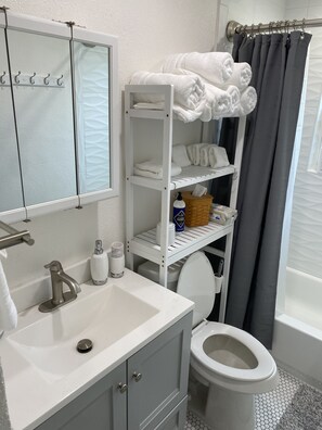 Een bad/douchecombinatie, een haardroger, handdoeken, zeep