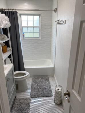 Een badkamer met toilet, bad en raam.