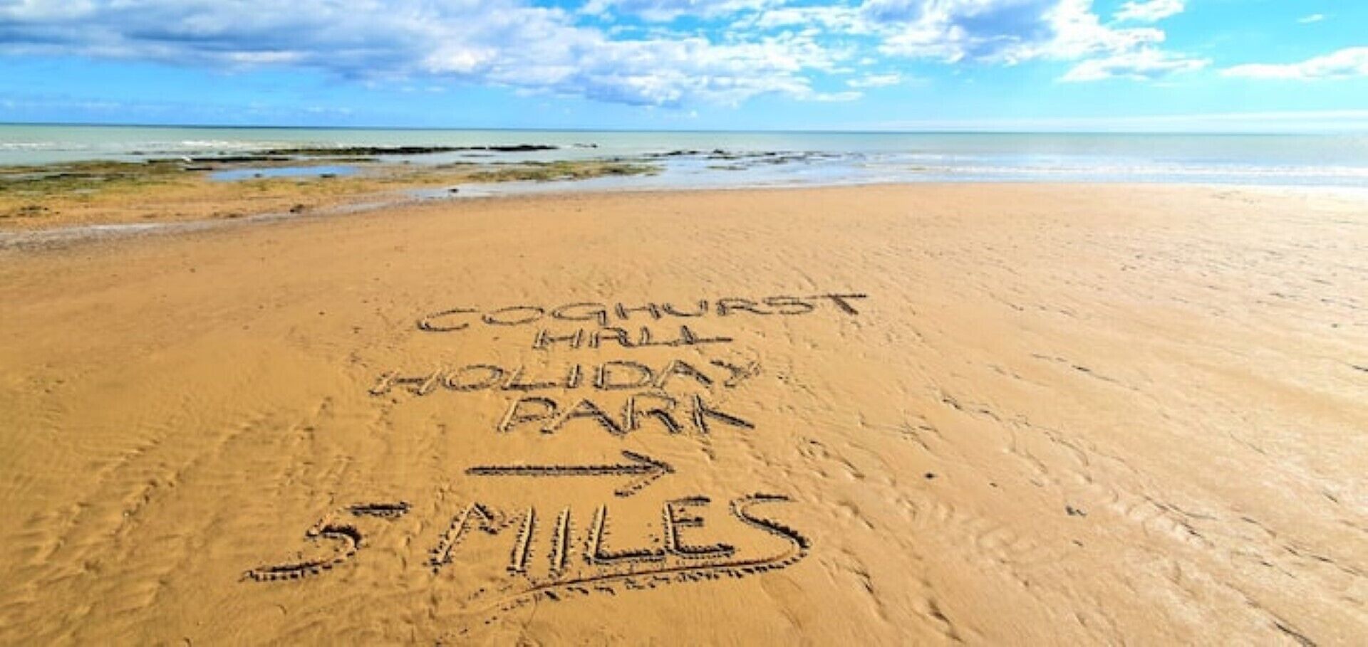A beach with 'Coghurst Holiday Park' and '5 MILES' marked on the sand.