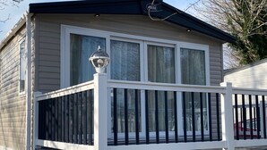 Een klein, gelijkvloers gebouw met een witte gevel en een zwart dak. Het heeft een witte veranda met een zwarte balustrade en een kleine lantaarnpaal.
