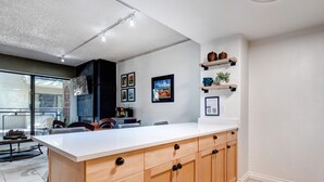 A modern kitchen with a large island, wooden cabinets, and a dining area with chairs.