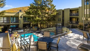 A hotel with a pool area, outdoor seating, and a view of the surrounding landscape.