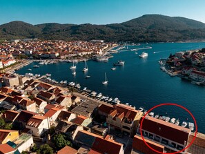 Un pueblo costero con un puerto deportivo lleno de barcos, rodeado de edificios residenciales con tejados de teja roja.