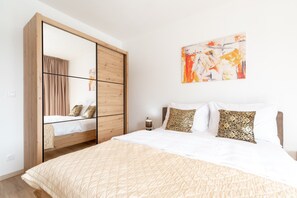 A bedroom with a bed, a wardrobe, a bedside table, and a painting on the wall. - Apartments & Rooms Fisherman's Luck - One-Bedroom Apartment with Terrace and Sea View (Vela Luka)