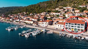 Eine Küstenstadt mit einem Hafen voller Boote, umgeben von Wohnhäusern mit roten Ziegeldächern.