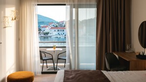 Ein Hotelzimmer mit Balkon, einem Bett, einem Schreibtisch und einem Stuhl.