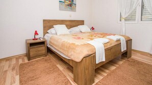 A neatly arranged bedroom with a wooden bed, a nightstand, a red lamp, and a painting on the wall. - Apartment Pascal - One Bedroom Apartment with Terrace and Sea View (Janjina)