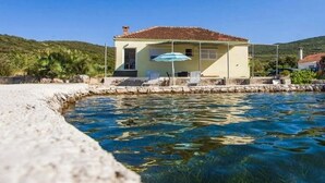 A coastal house with a tiled roof, a small porch, and a clear blue pool. - Apartment Pascal - One Bedroom Apartment with Terrace and Sea View (Janjina)