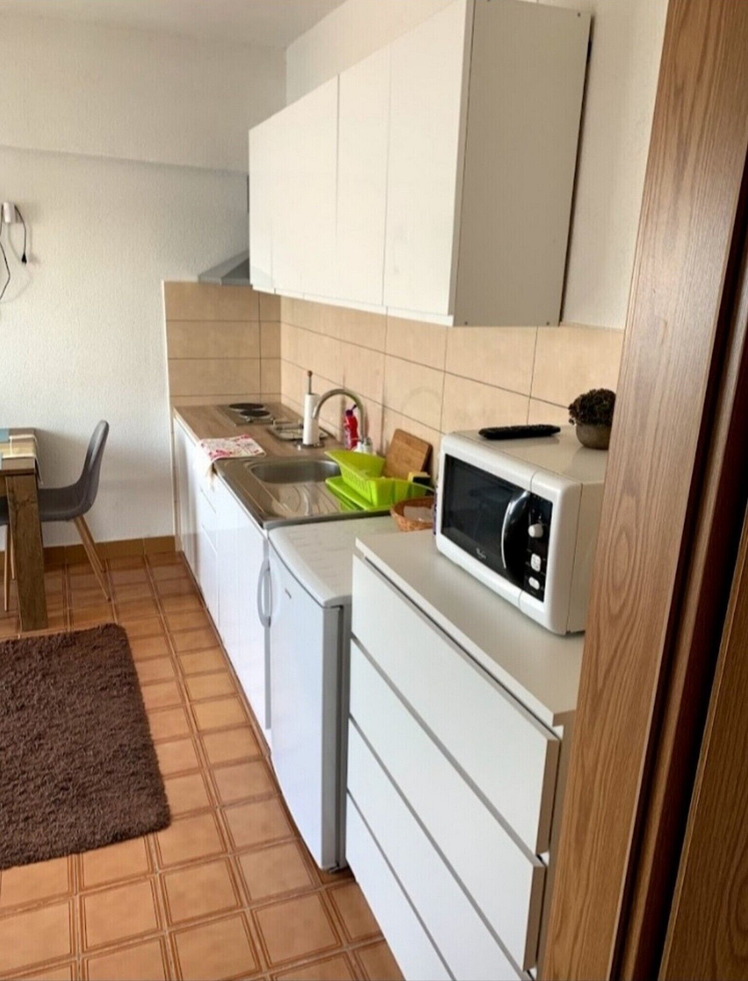 Eine kleine Küche mit Mikrowelle, Spüle und kleinem Kühlschrank.