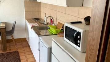 Eine kleine Küche mit Mikrowelle, Spüle und kleinem Kühlschrank.