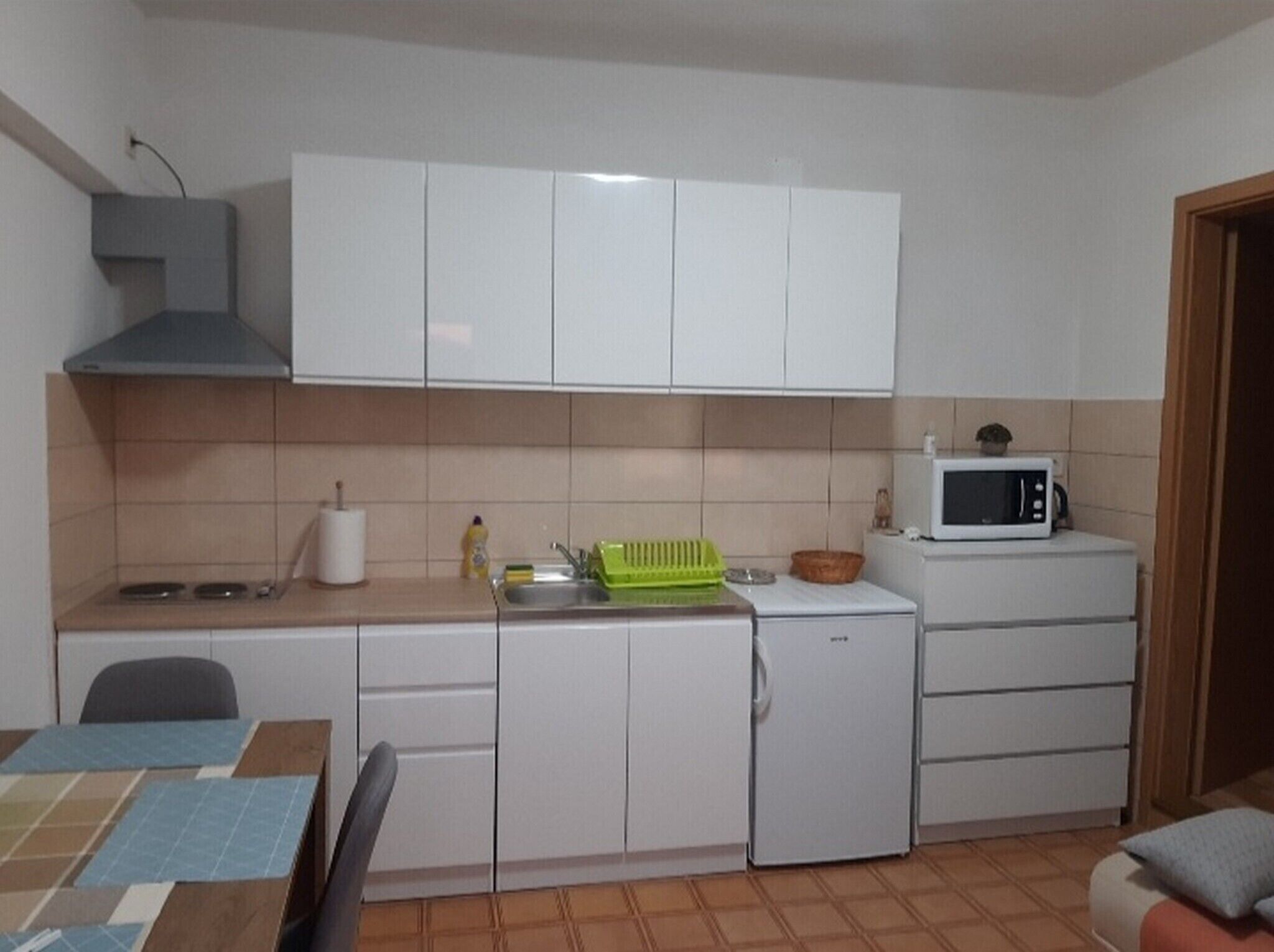 A compact kitchen with white cabinets, a microwave, a small sink, and a stove.