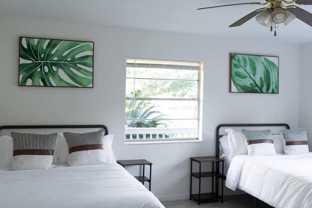 A hotel room with two beds, a window with a view, and artwork on the walls.