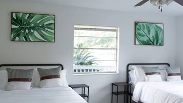 A hotel room with two beds, a window with a view, and artwork on the walls.