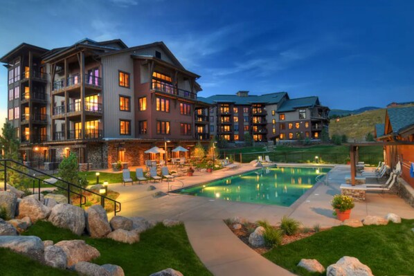 Enjoy the hotel's pool surrounded by a paved deck and lush lawn, with outdoor seating areas and balconies on each floor.
