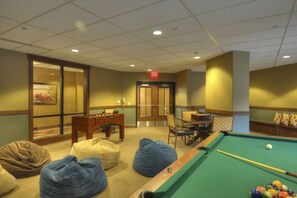 Relax in a cozy space with a pool table, artwork, and comfortable seating areas.