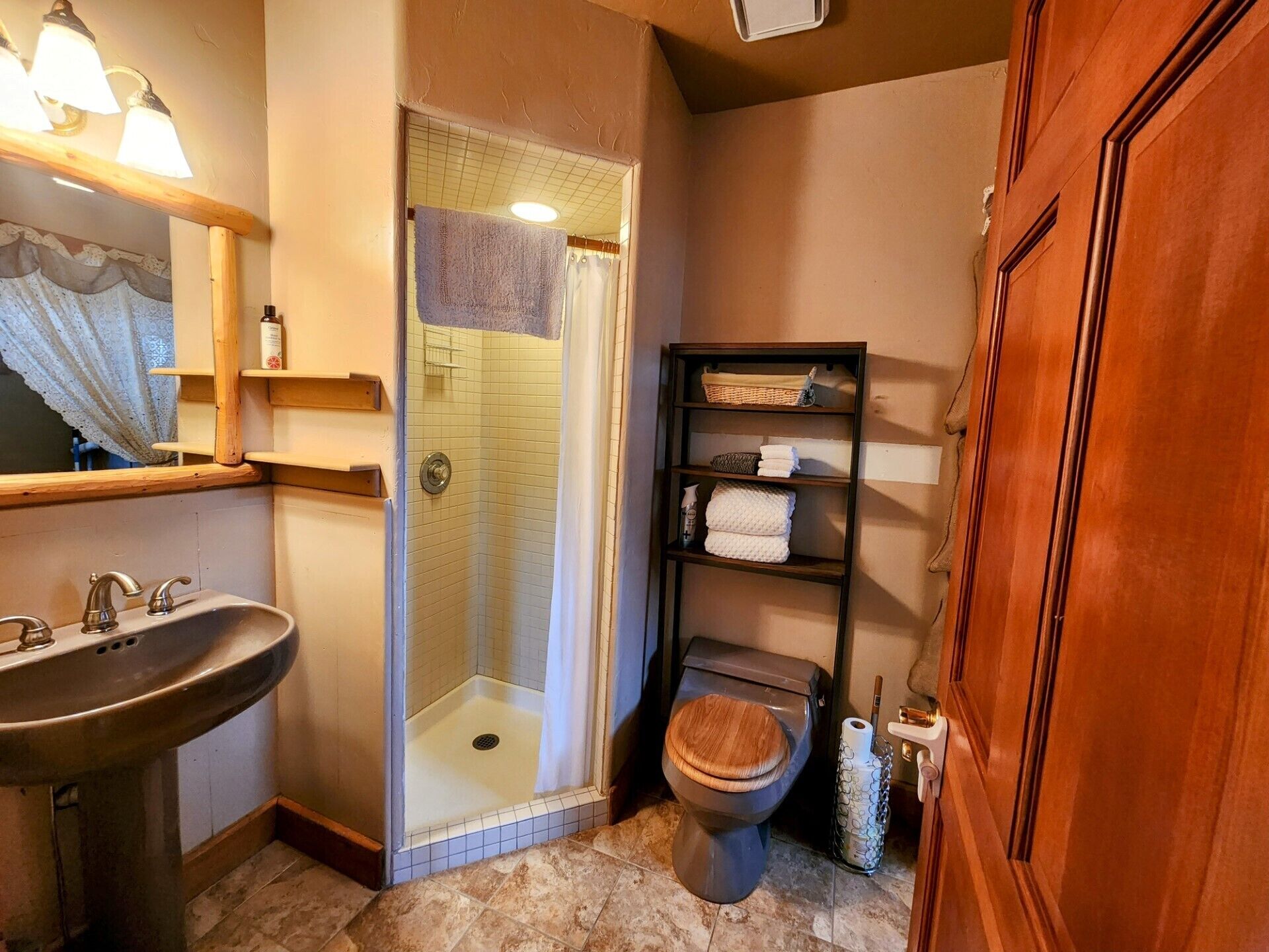Ein Badezimmer mit Dusche, Toilette, Waschbecken und Regalen mit Handtüchern.