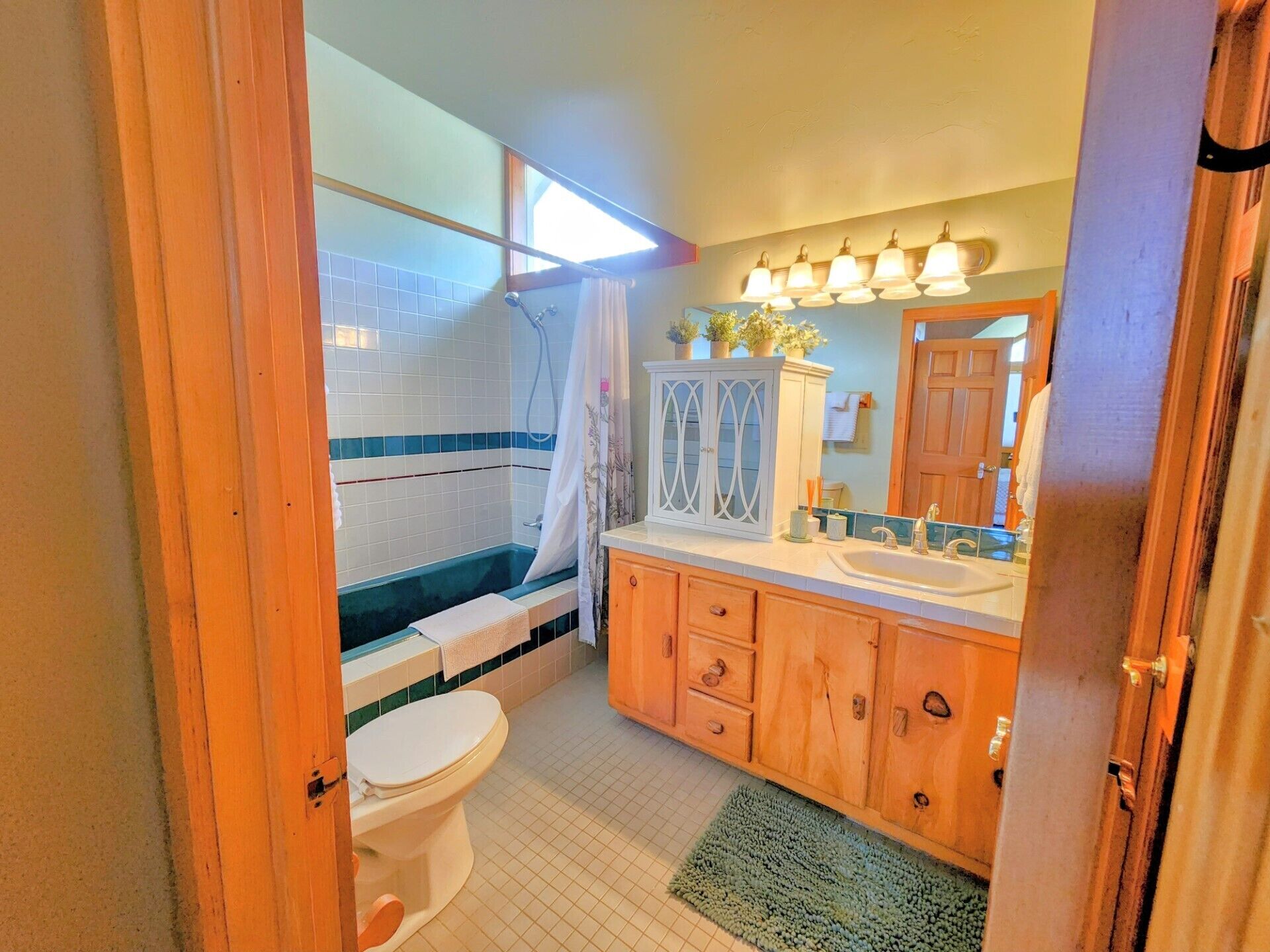 Ein Badezimmer mit Badewanne, Toilette, Waschbecken und Holzschränken.