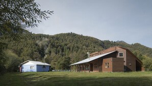 A rustic wooden barn with a sloped roof and a smaller blue shed nearby.