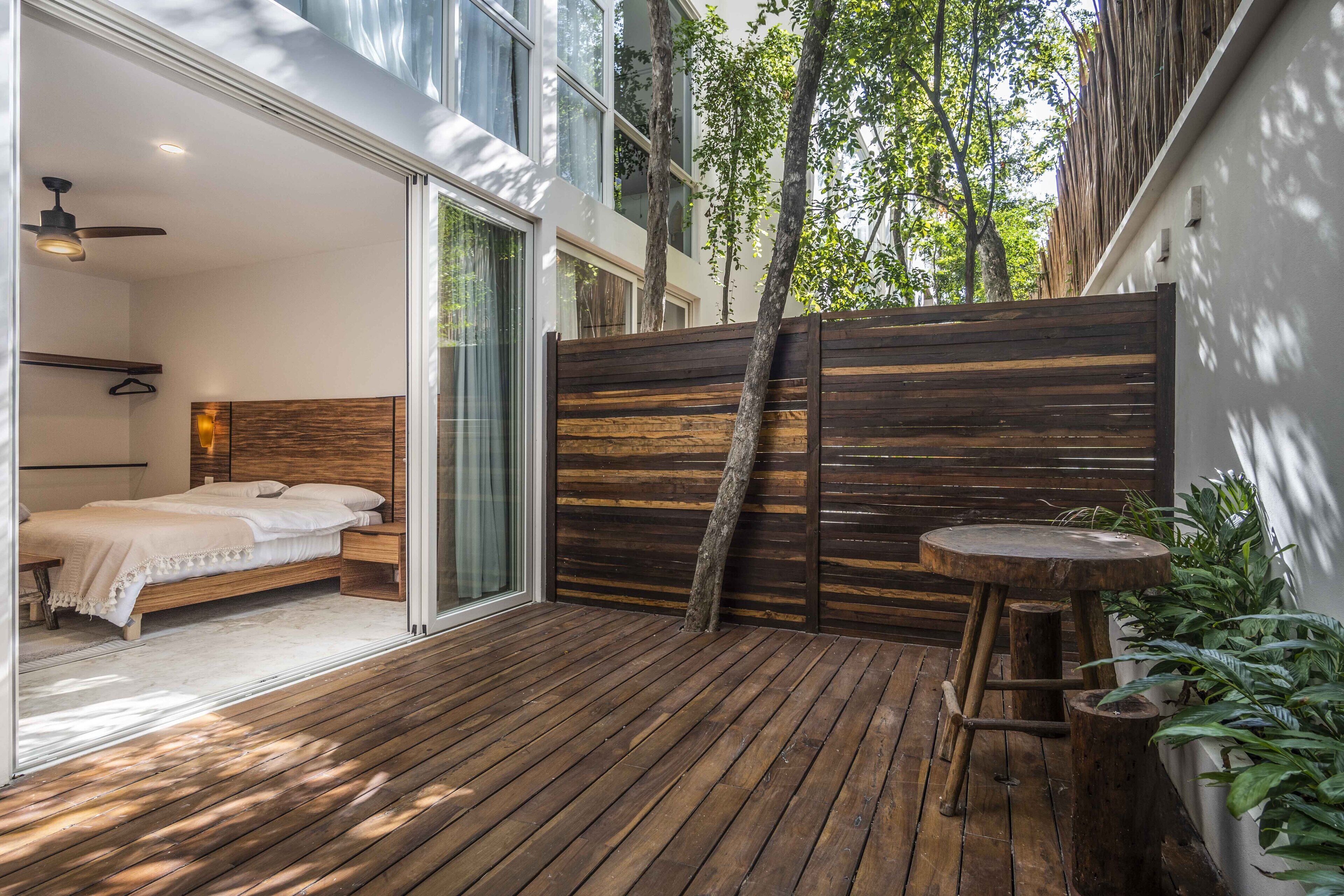 Una camera da letto moderna con pavimento in legno, un letto e una porta scorrevole in vetro che dà su un balcone.