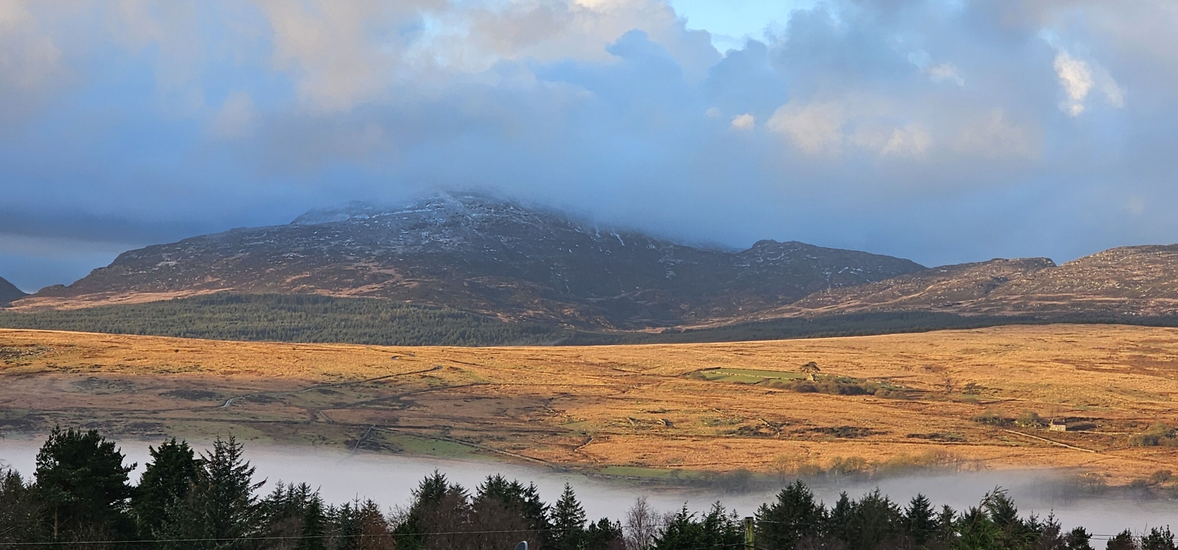 A mountainous landscape with a valley and a body of water in the foreground.