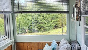 A covered porch with wicker furniture, a view of greenery, and a wooden ceiling. - Log Cabin - Free Parking, Garden & pet Friendly (Blaenau Ffestiniog)