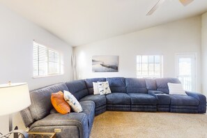 A living room with a large sectional sofa, a lamp, and a painting on the wall.