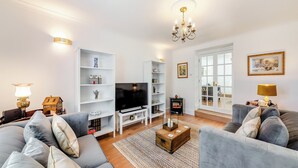 A living room with a sofa set, a television, a fireplace, and a bookshelf.
