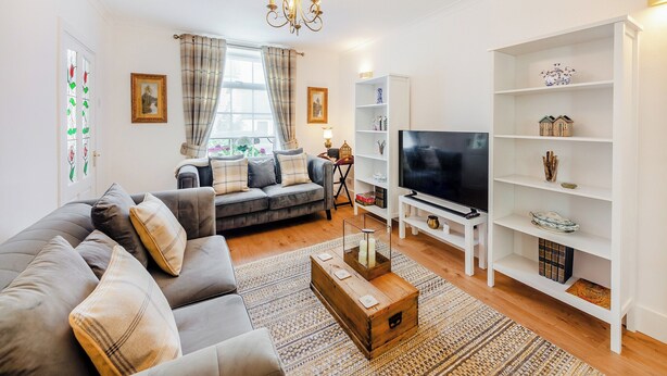 A living room with a sofa, TV, and white shelving unit.