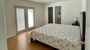 A bedroom with a bed, a nightstand, a lamp, a door, and a window. - 3 Bedroom home with large pool. Great location. (Port St. Lucie)