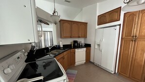 A compact kitchen with white appliances, wooden cabinets, and a striped rug. - 3 Bedroom home with large pool. Great location. (Port St. Lucie)