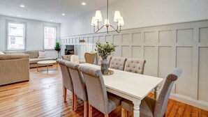 A dining area with a white table, grey upholstered chairs, and a chandelier. - Luxury Manor on Mulberry in the heart of Downtown Lanc (Lancaster)