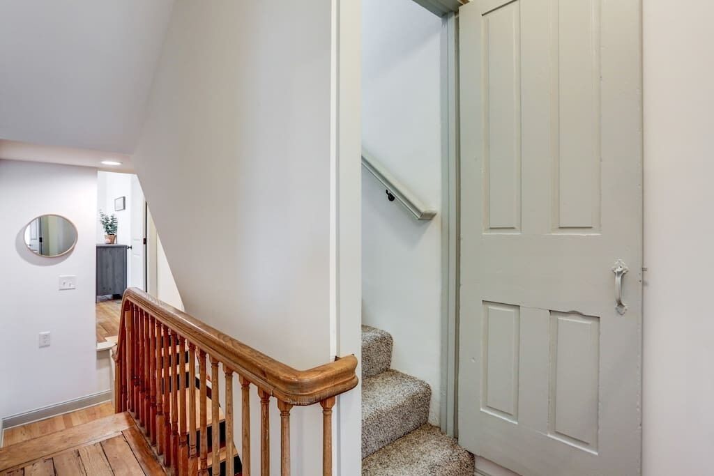 A staircase with wooden handrails and carpeted steps leading to a white door with a handle.