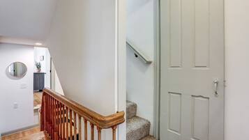 A staircase with wooden handrails and carpeted steps leading to a white door with a handle.
