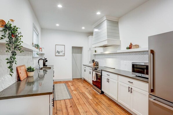 A modern kitchen with white cabinetry, a wooden countertop, and a built-in oven.