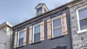 A two-story building with a dark facade, wooden shutters on the windows, a black door, and a small porch with a metal railing. - Luxury Manor on Mulberry in the heart of Downtown Lanc (Lancaster)