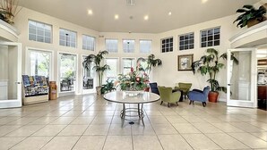 A spacious lobby with a round table, several chairs, and potted plants. - Newly Renovated First Floor 2Bed & 2 Bath, Near Disney (Kissimmee)