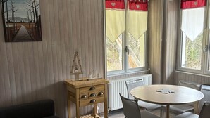 A modern living room with a sofa, a dining table with chairs, a wooden side table, and a hanging light fixture. - LES COMBES apartment-chalet sleeps 4 classified 3 * LES ROUSSES (Les Rousses)