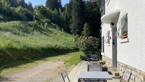 A patio with outdoor seating and a view of a forested hillside. - LES COMBES apartment-chalet sleeps 4 classified 3 * LES ROUSSES (Les Rousses)