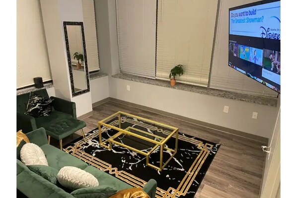 Relax in this stylish living room with a green sofa, black and white rug, and a large mirror.