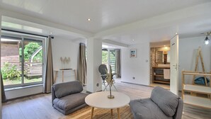 Ein modernes Wohnzimmer mit einem runden Tisch, zwei grauen Sofas und einem großen Fenster mit Vorhängen.