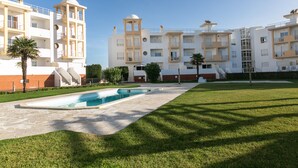 A modern apartment complex with a swimming pool, multiple balconies, and a well-maintained lawn. - Paradise Place - Pool Balcony (Nazaré)