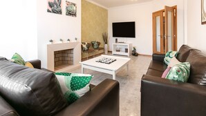 A living room with a fireplace, a flat-screen TV, and a sofa. - Paradise Place - Pool Balcony (Nazaré)