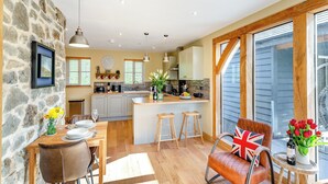 A modern kitchen with a stone wall, wooden counter, and a dining area with a table and chairs.