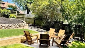 A backyard with a grassy lawn, wooden deck, and outdoor furniture.
