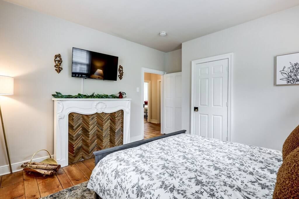 Quarto com cama, lareira, televisão e porta que dá para outro cômodo.