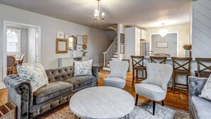 A spacious living room with a grey sofa, a round coffee table, and a staircase leading to another level.
