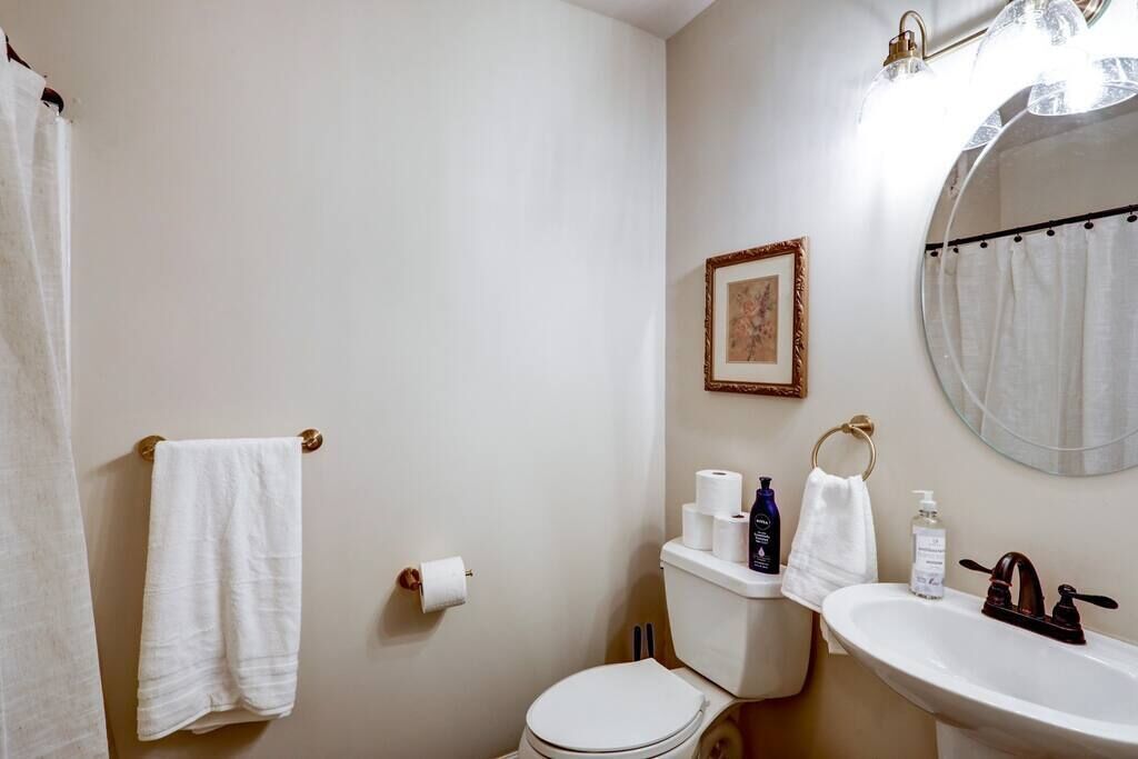 Un baño con inodoro, lavamanos y un cuadro en la pared.